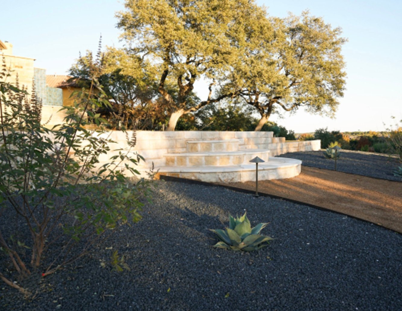 Graded gravel bed and stone retaining wall managing site drainage