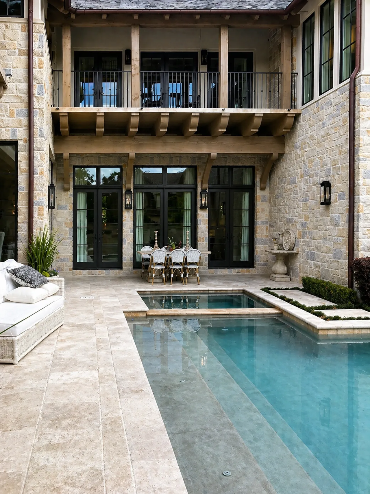 Backyard pool courtyard with a covered porch and mature landscaping by Strong Landscaping