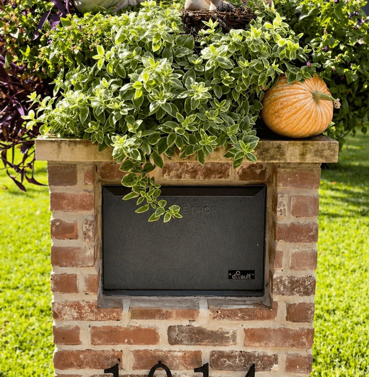 Brick mailbox planter topped with pumpkins and trailing greenery in Houston