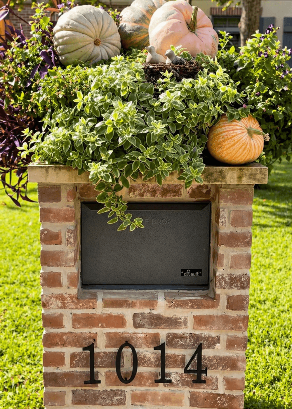 Brick mailbox and planter box dressed with seasonal decor by Strong Landscaping