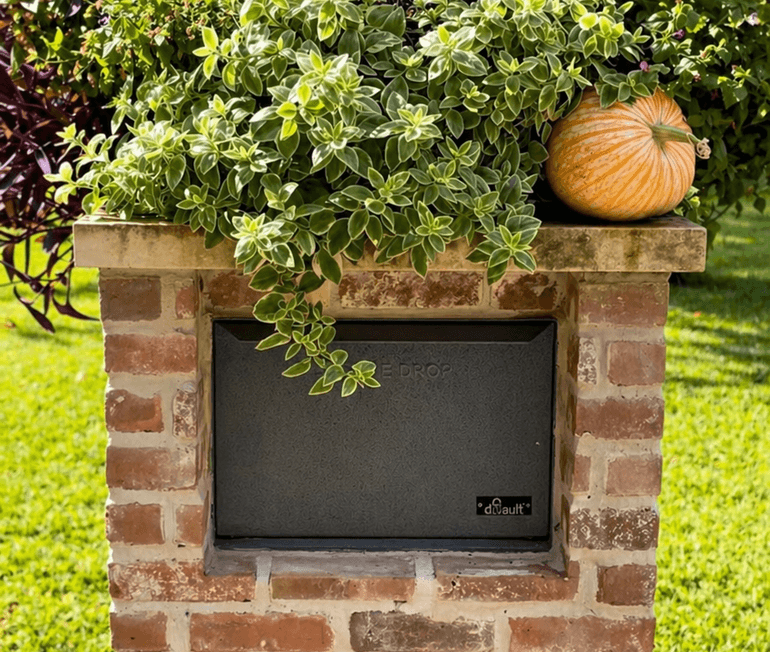 Brick mailbox planter topped with pumpkins and trailing greenery in Houston