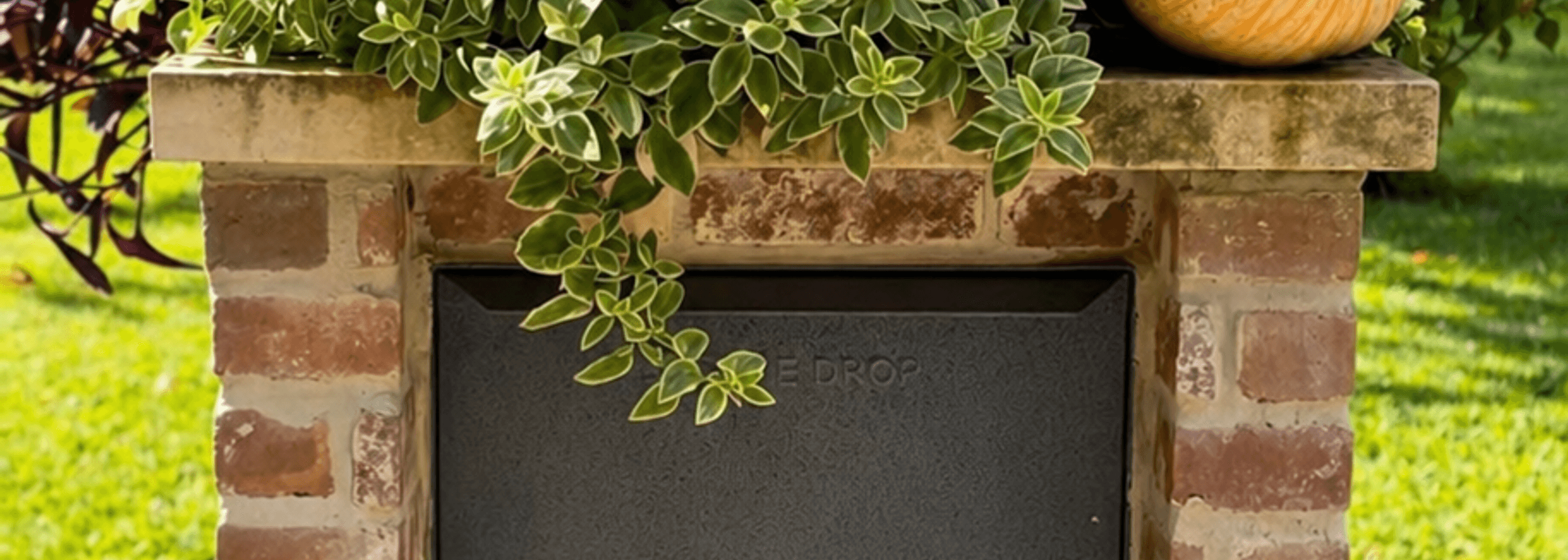 Brick mailbox planter with warm seasonal lighting and holiday decor at a Houston home entry