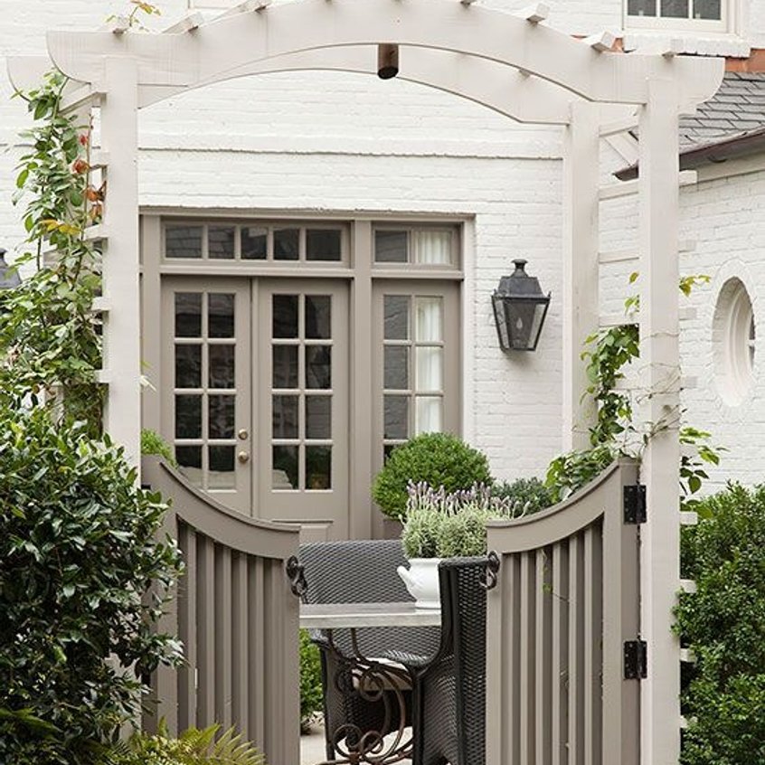 Front entry gate with a paved courtyard and potted planters designed by Strong Landscaping