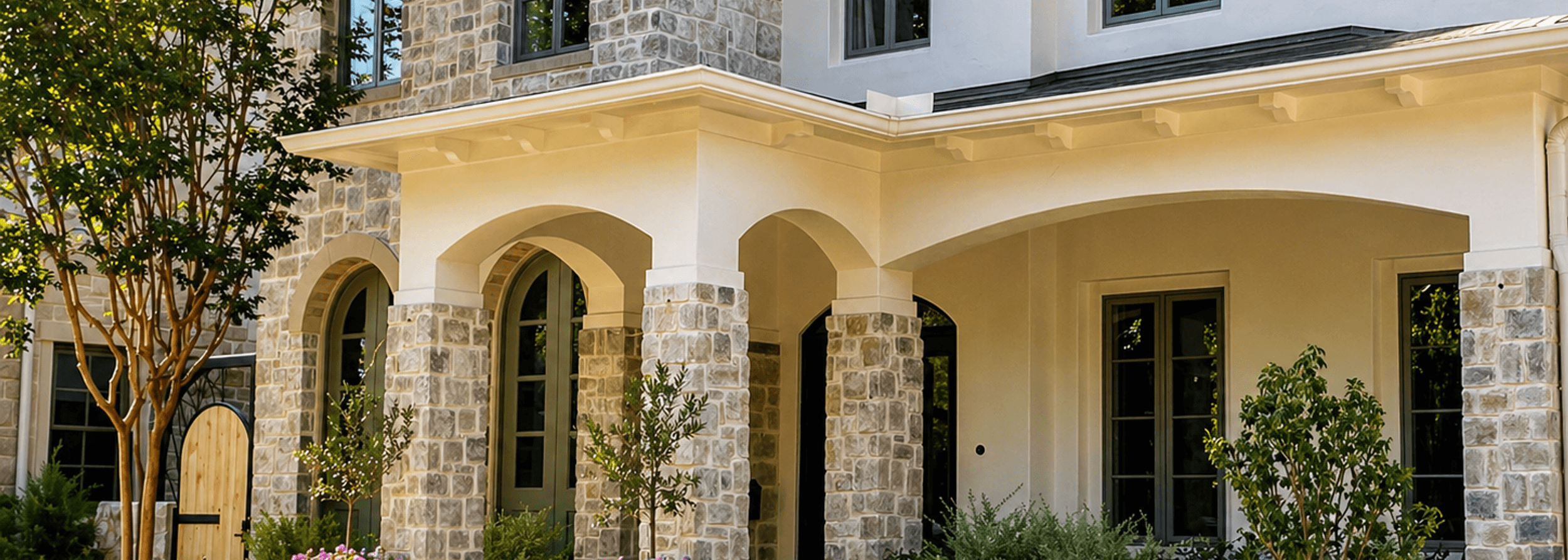Front-yard landscaping with a healthy green lawn and flower beds at a stone home in Greater Houston, built by Strong Landscaping