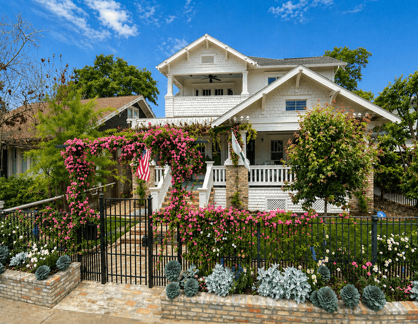 Designed front-yard rose garden with an entry gate and flower beds by Strong Landscaping
