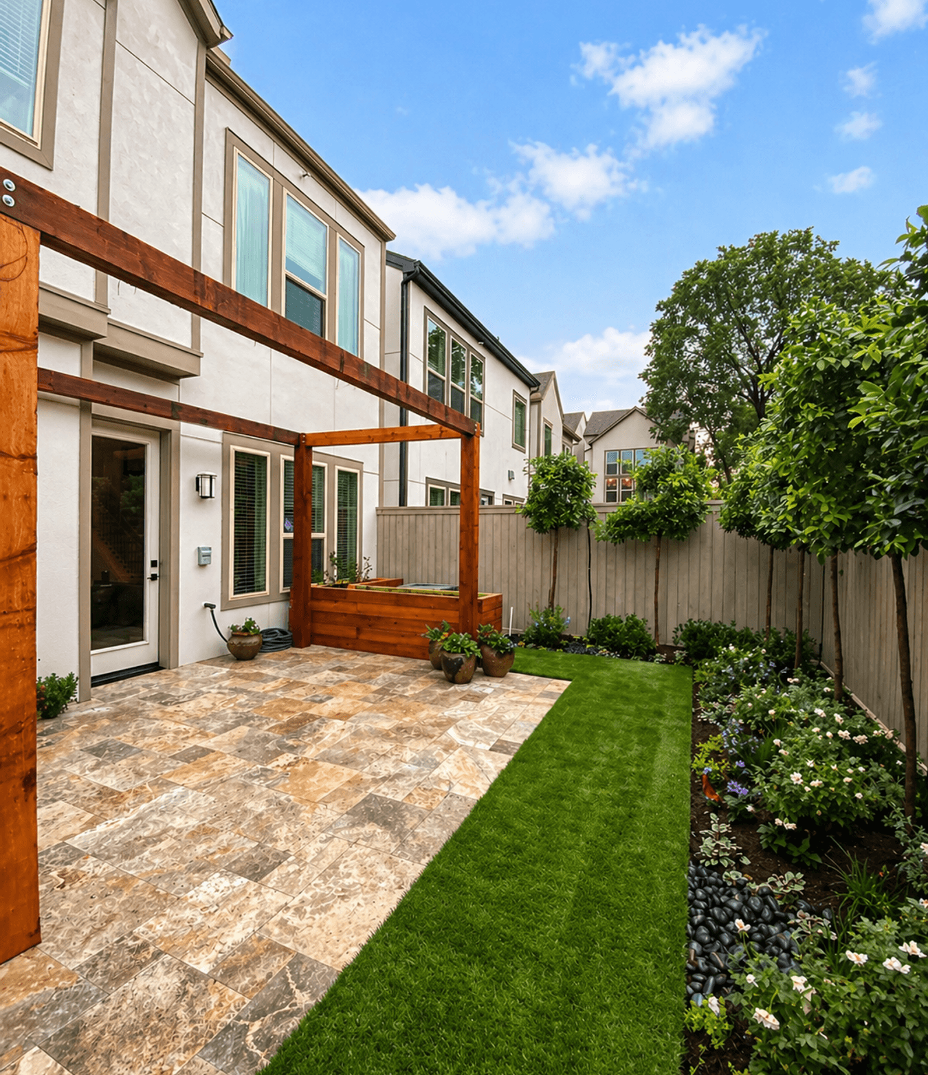Small backyard with a stone patio, artificial turf, and garden beds, the kind of tight-lot yard Strong Landscaping builds in EaDo, Houston, TX